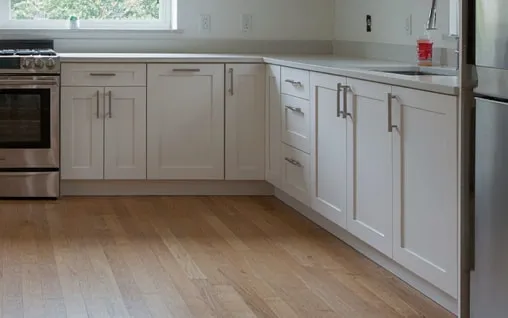 The same kitchen after cleaning, with clear counters and a clean hardwood floor