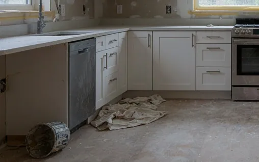 Kitchen just after renovation, with dust on the floor, a drop cloth and a paint bucket